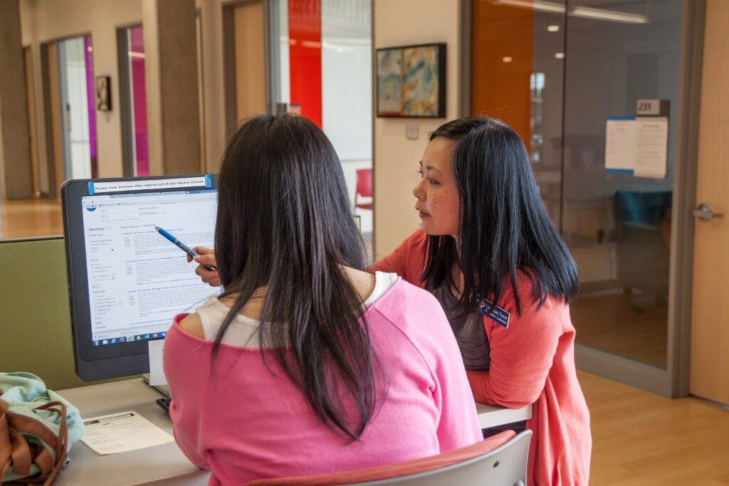 tutor leans over student at computer