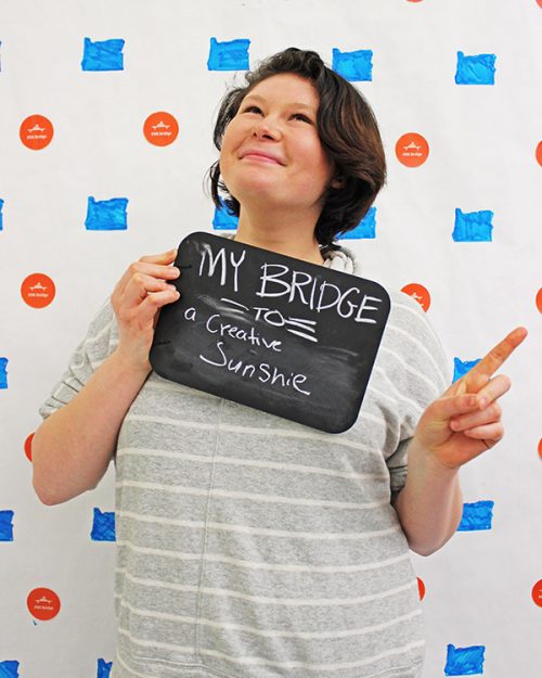 Student holding a sign that says my bridge to creative sunshine