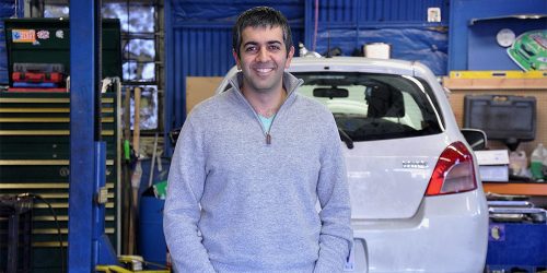 SBDC Client Farhad Ghafarzade standing in front of cars at Green Drop Garage