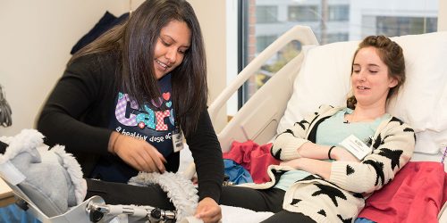 Certified Nursing Assistant trainees take turns caring for each other in IHP practice hospital bed