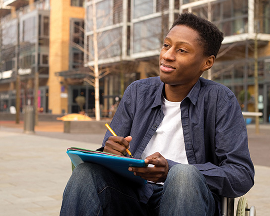 Student talking to someone else and writing in a notebook