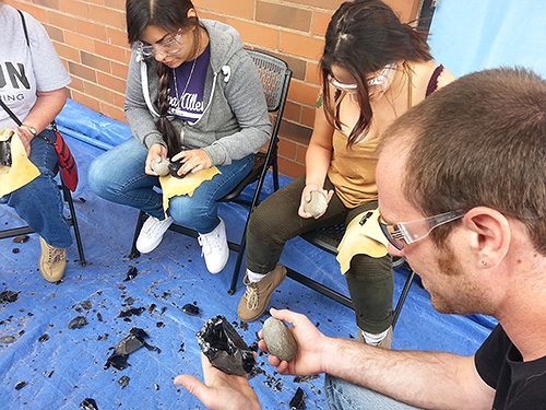 Students learning how to flintknapp (make stone tools)