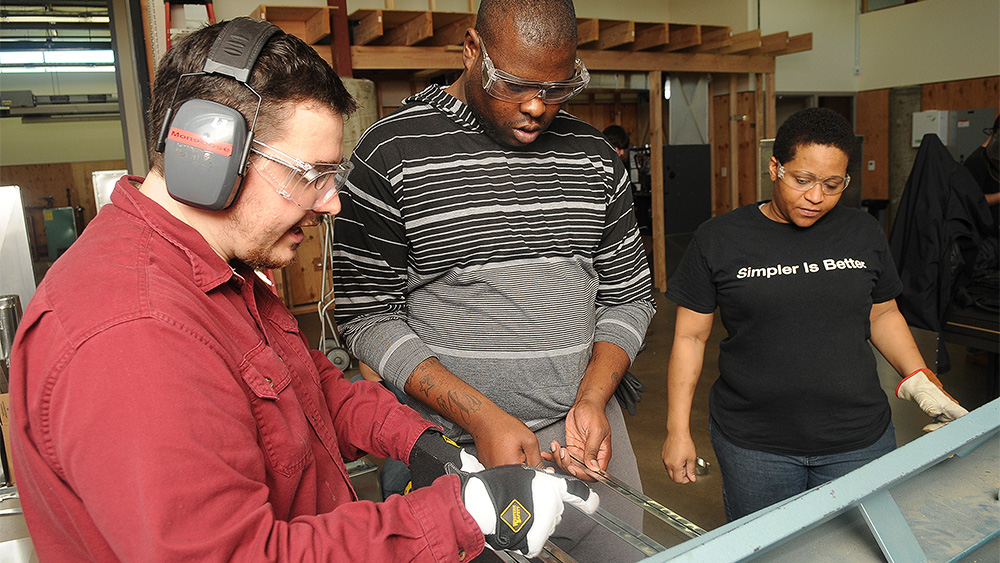 Instructor holding materials and talking about them with two students