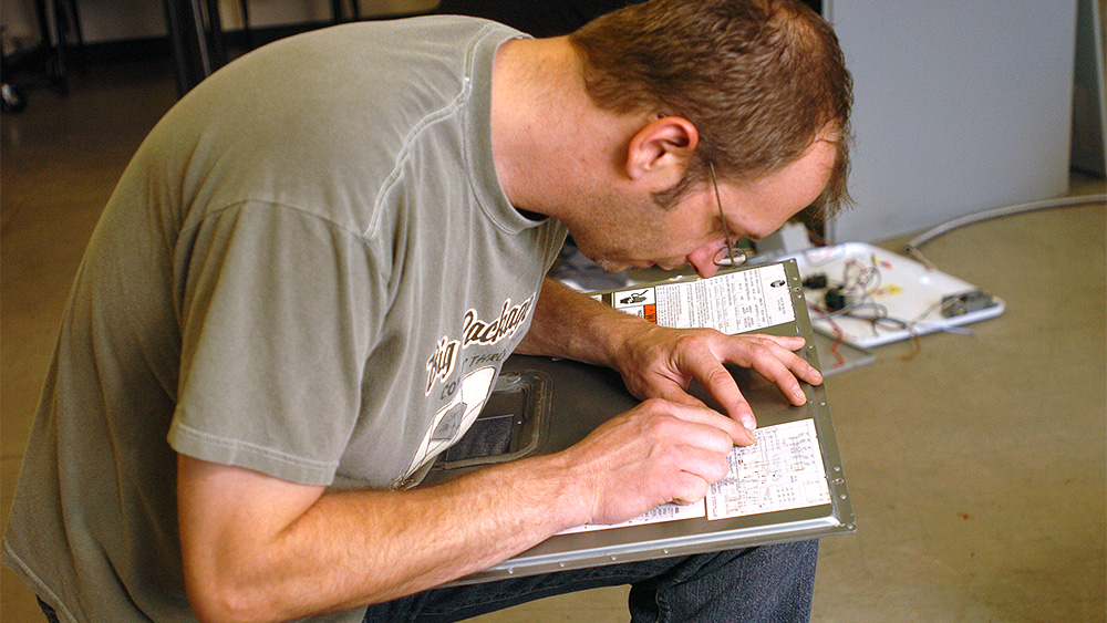 Student studying diagrams inside an electric box