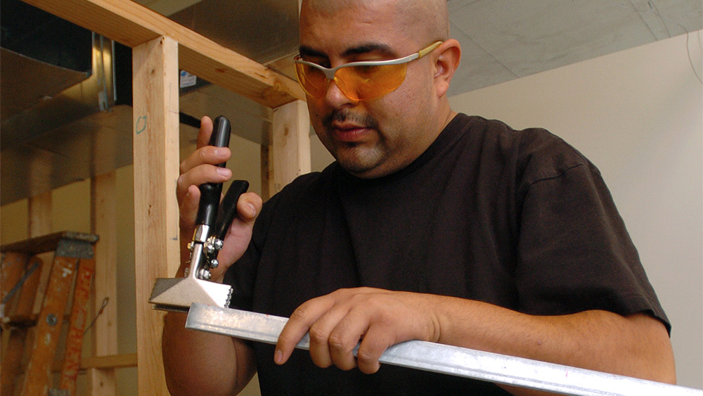 Student using a hammer with a piece of metal