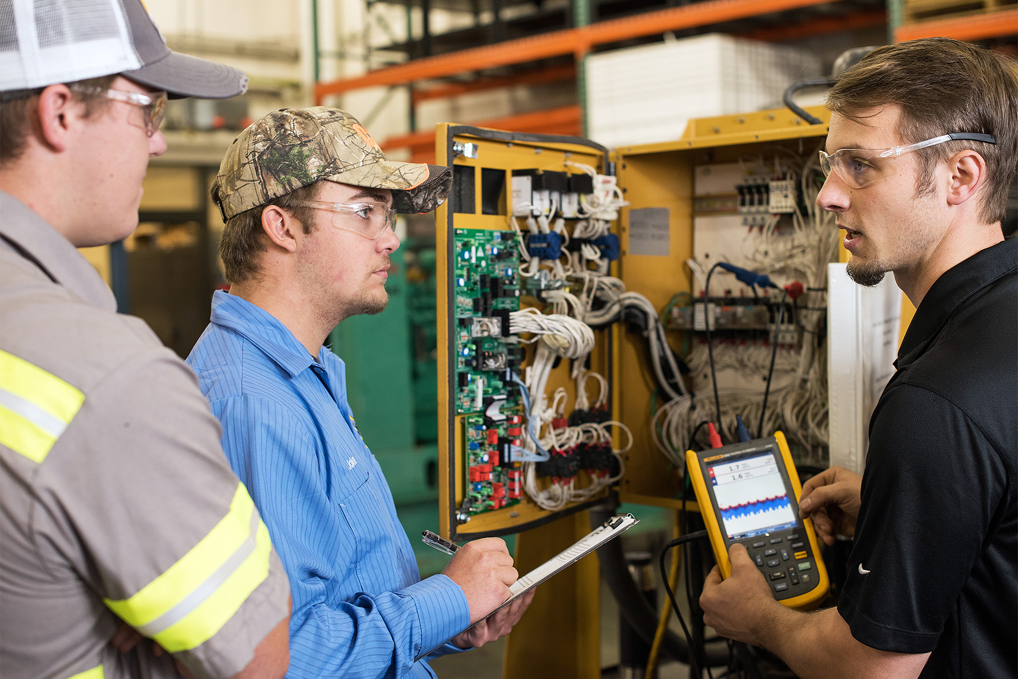 Apprenticeship instructor holding with an electrical gauge and speaking to students