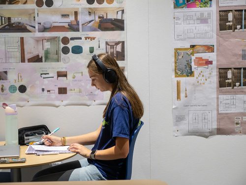 Student working on laptop in front of plans