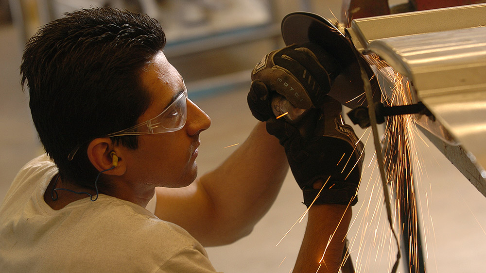 Student using a grinder on a car door and making sparks