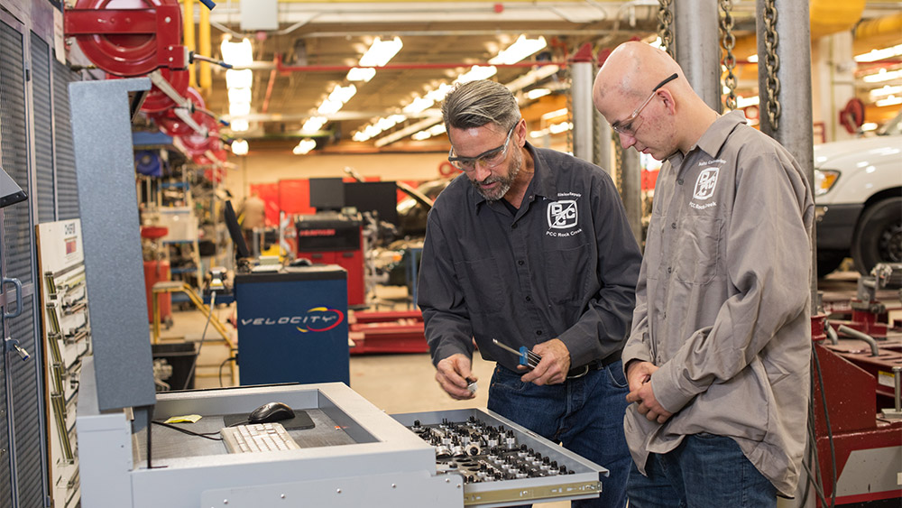 Instructor and a student looking at parts with the full large shop in the background