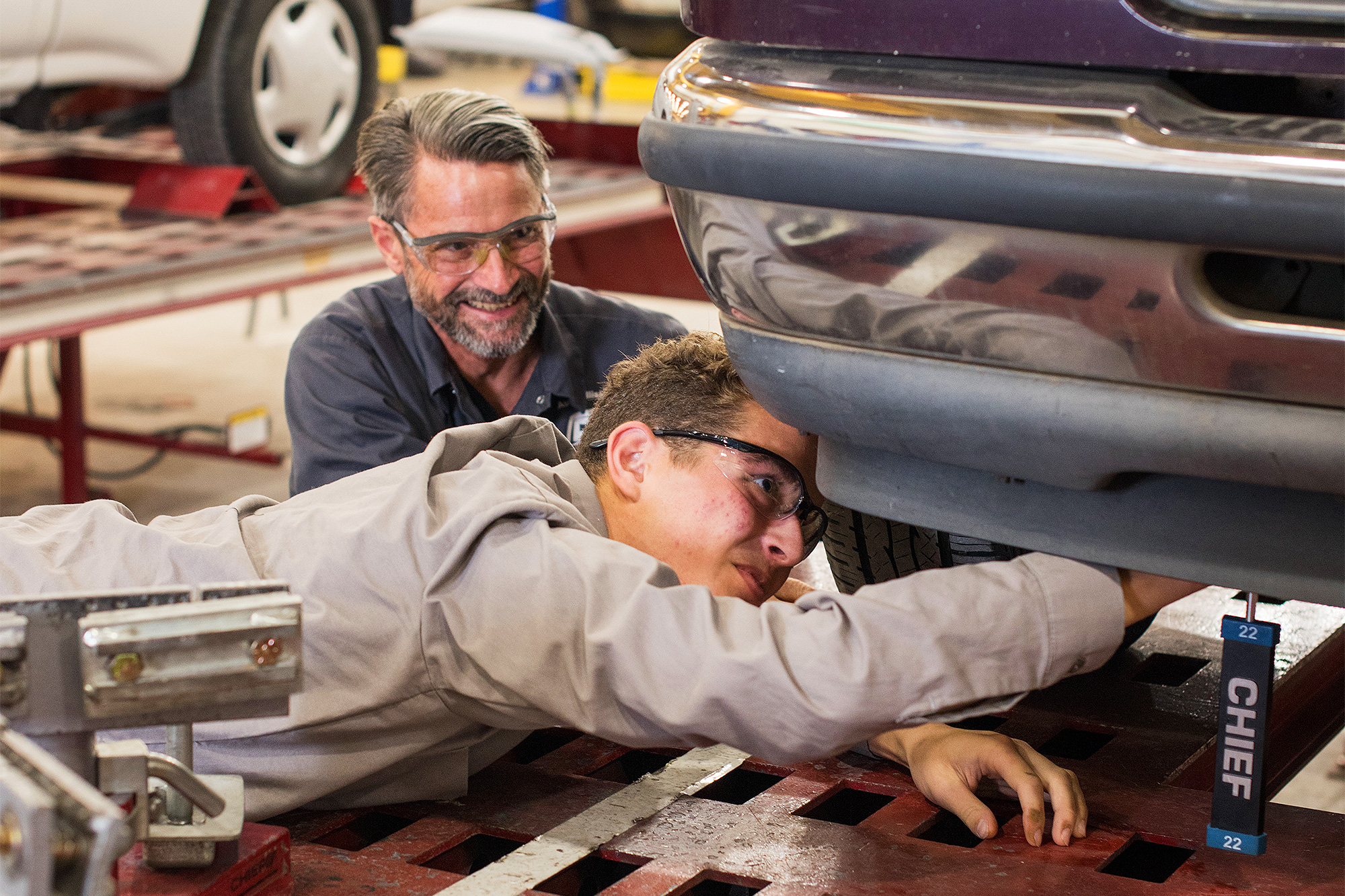 Auto Collision student laying below a car and doing a repair