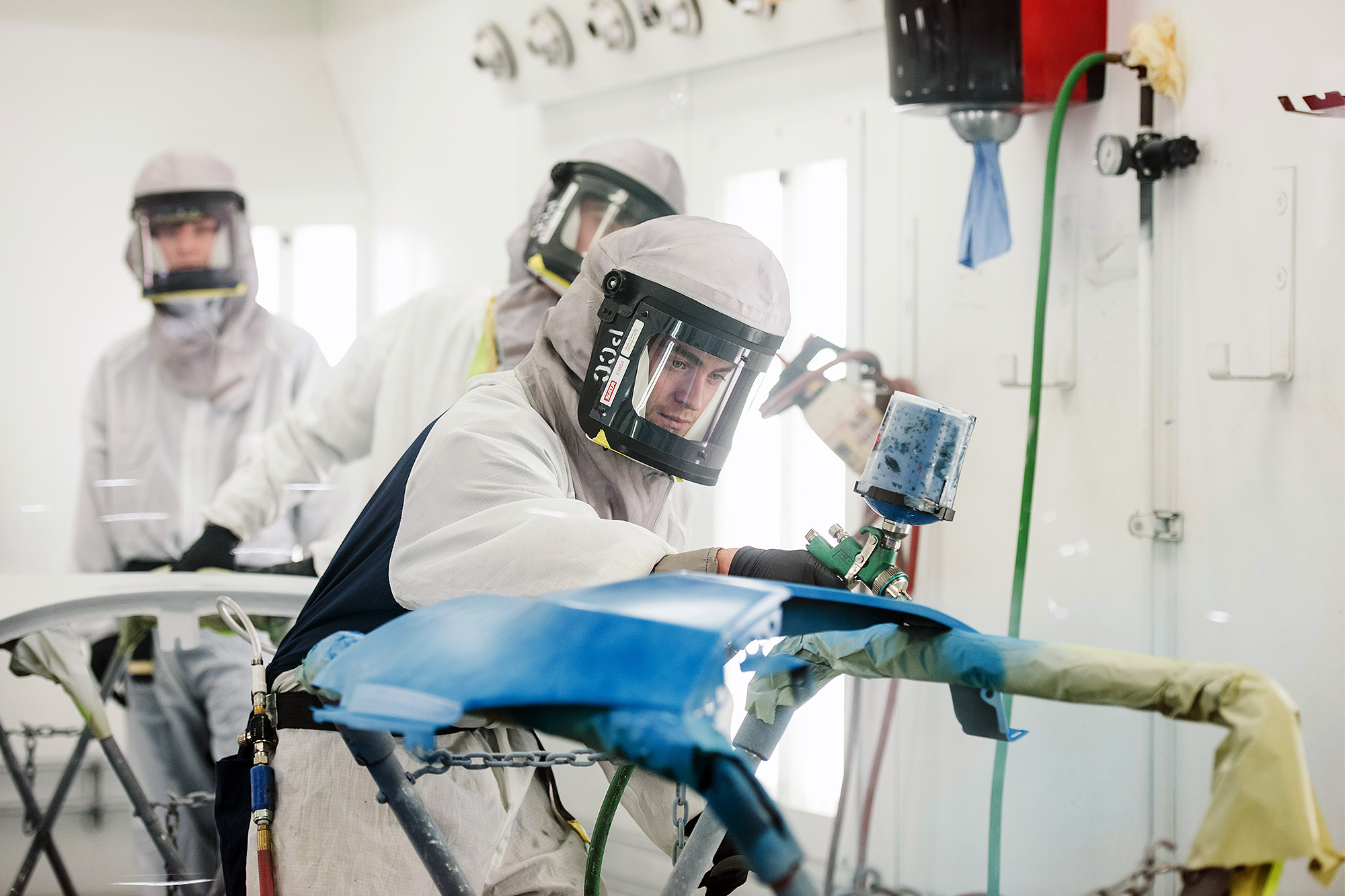 Auto Collision student painting a car door blue