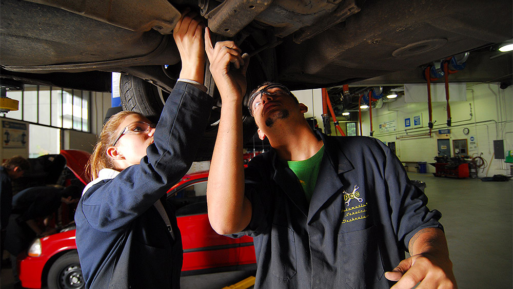 2 students inspecting a raised vehicle from below