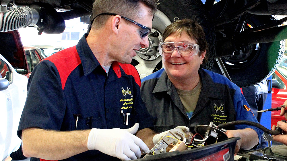 Student and instructor laughing while in the auto shop