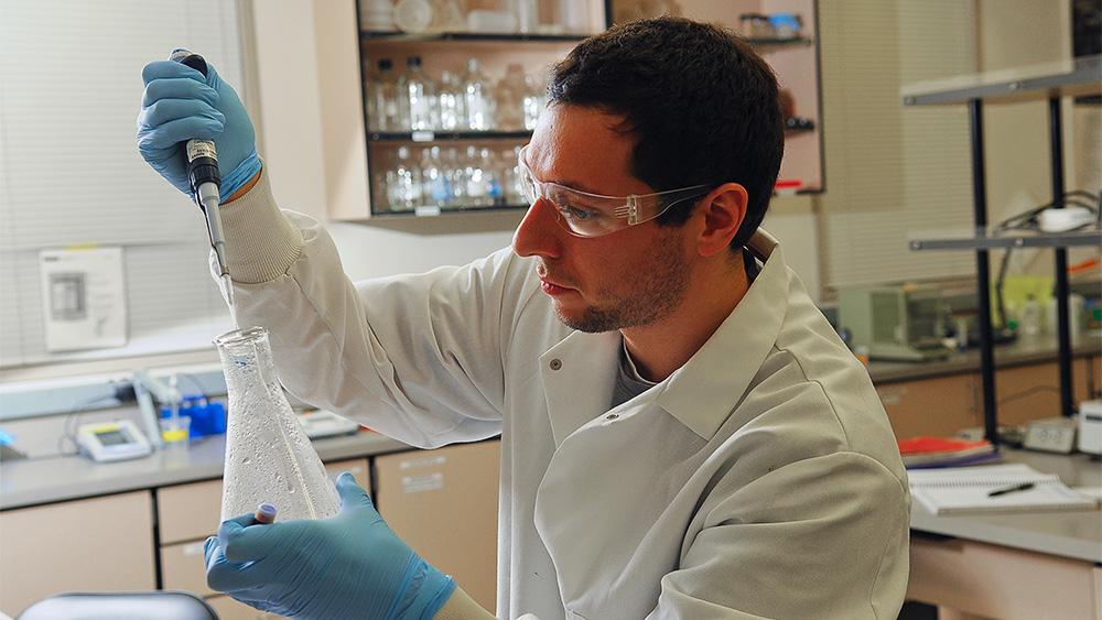 Student with a syringe and beaker in the lab