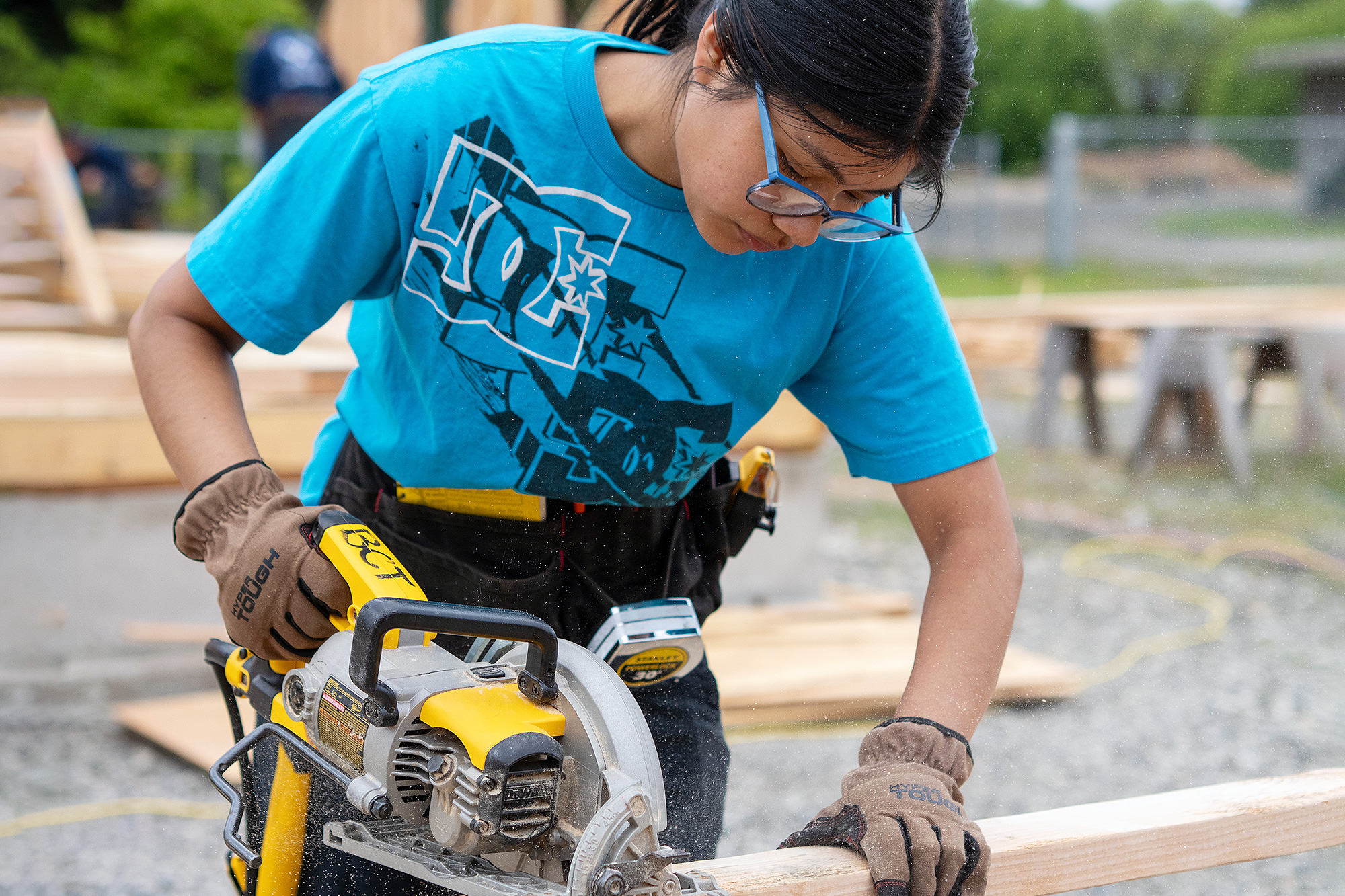 Building Construction student sawing a 2x4 piece of wood