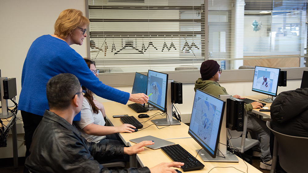 Instructor helping students on computers in class