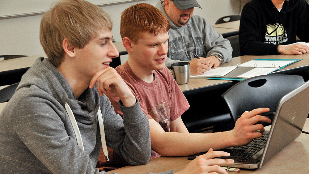 Students working on a laptop together in class