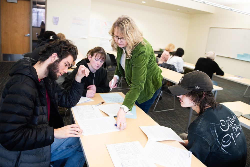Business students looking at handouts on a table together with the instructor