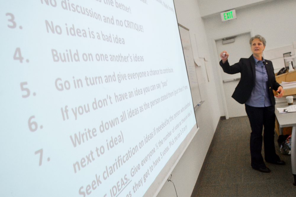 Instructor pointing to a presentation that has a list of tips for good management skills