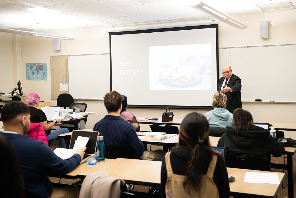 Instructor teaching from the front of class and gesturing toward a student