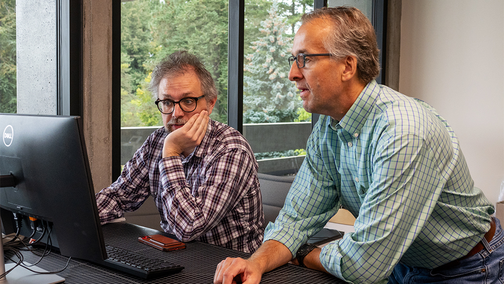 Instructor assisting a student on a computer in class