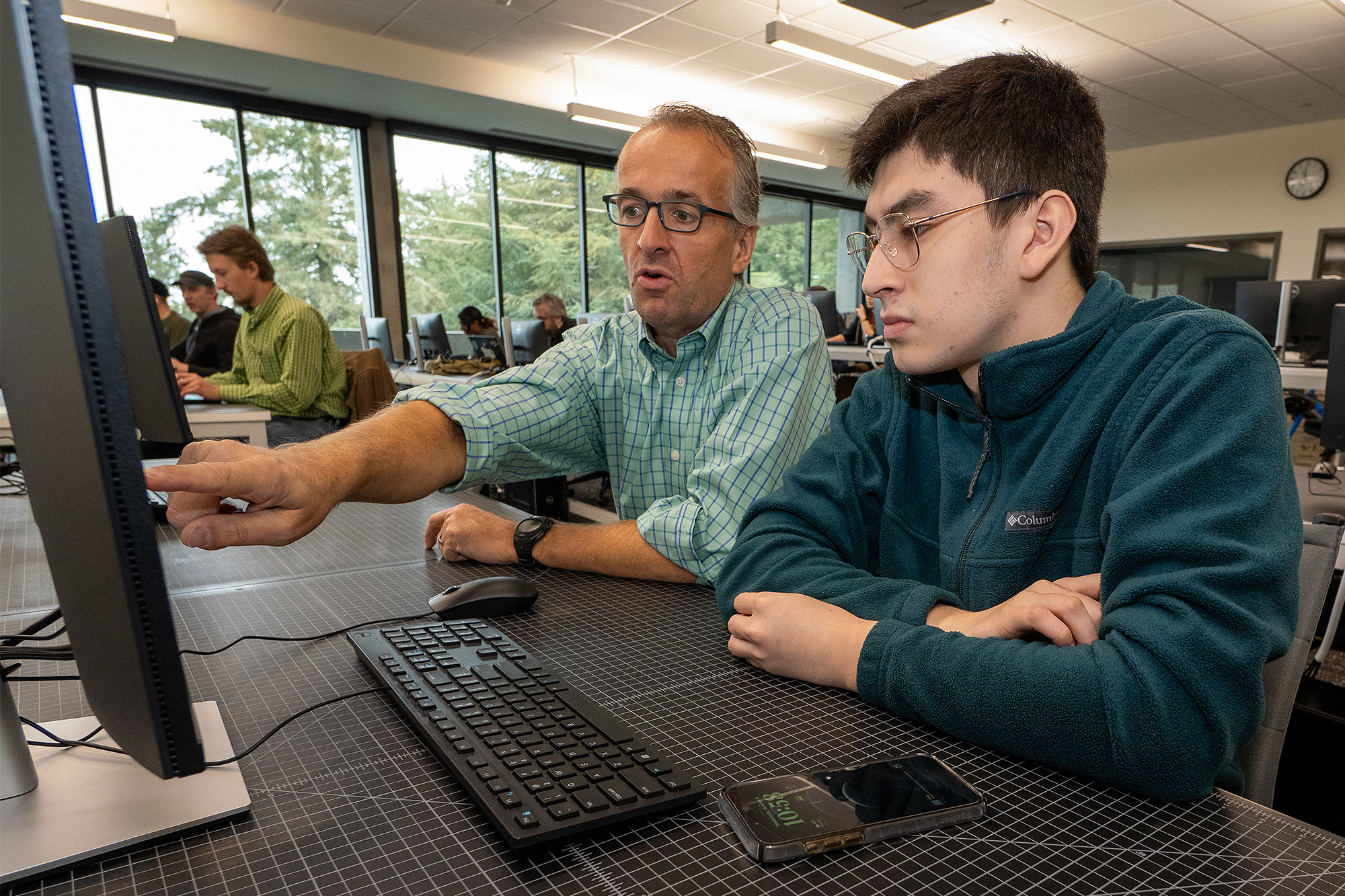 Java programming instructor helping a student in class