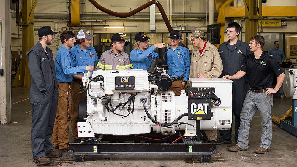 Students standing around a large CAT marine power generator in the shop