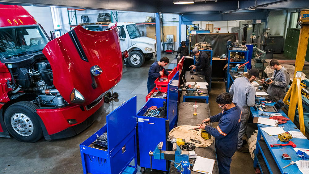 Diesel trucks in the shop with students working on them