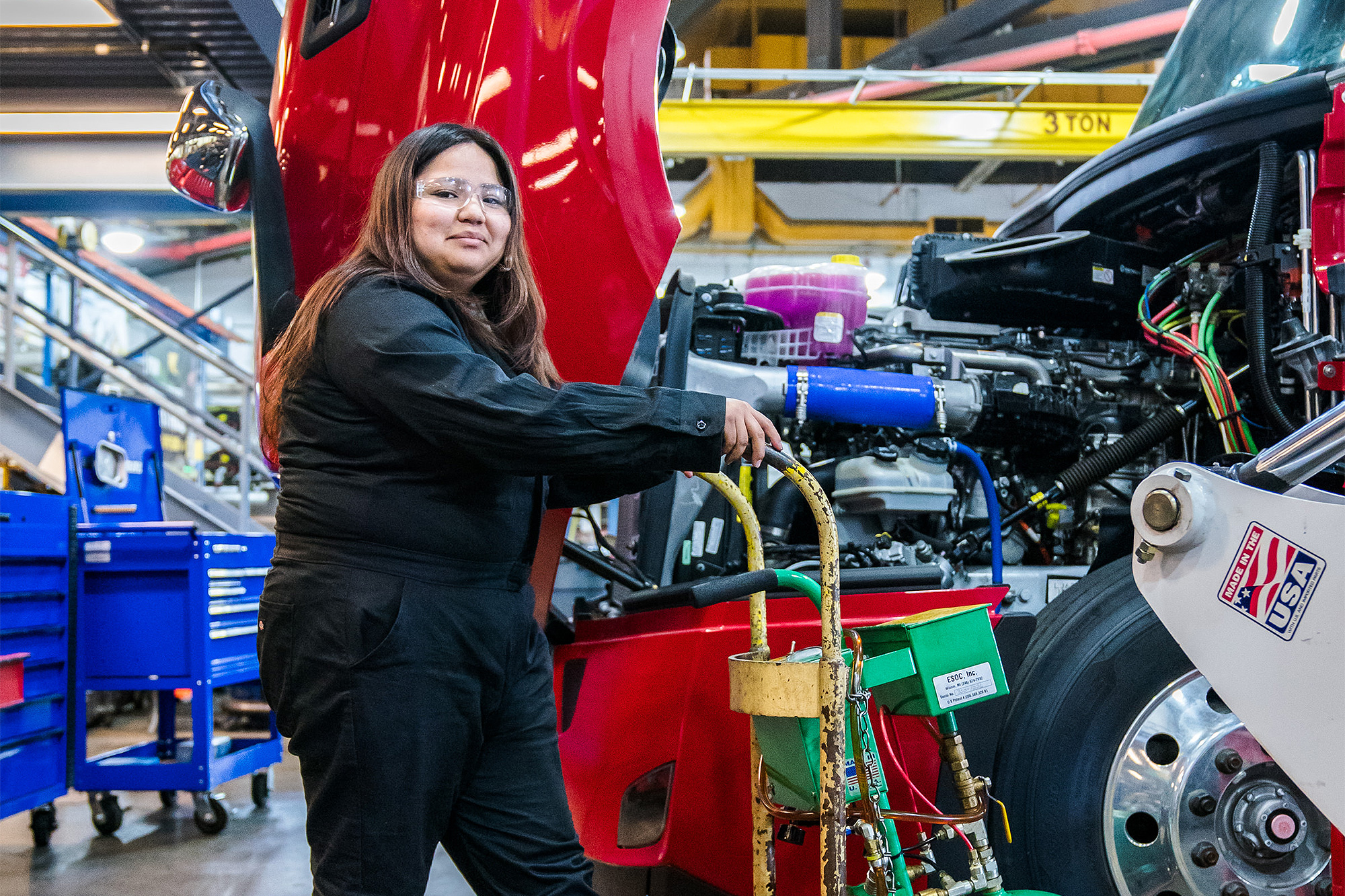 Diesel Service student standing next to a Freightliner truck with the engine cover open