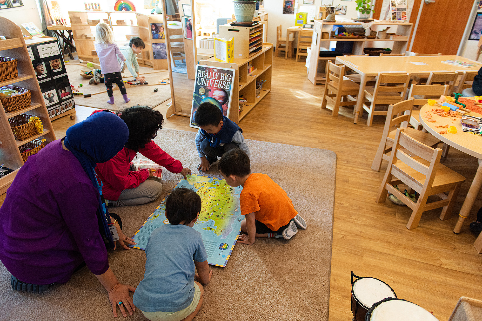 Aide teaching kids how to look at a map in the Childcare Development Center