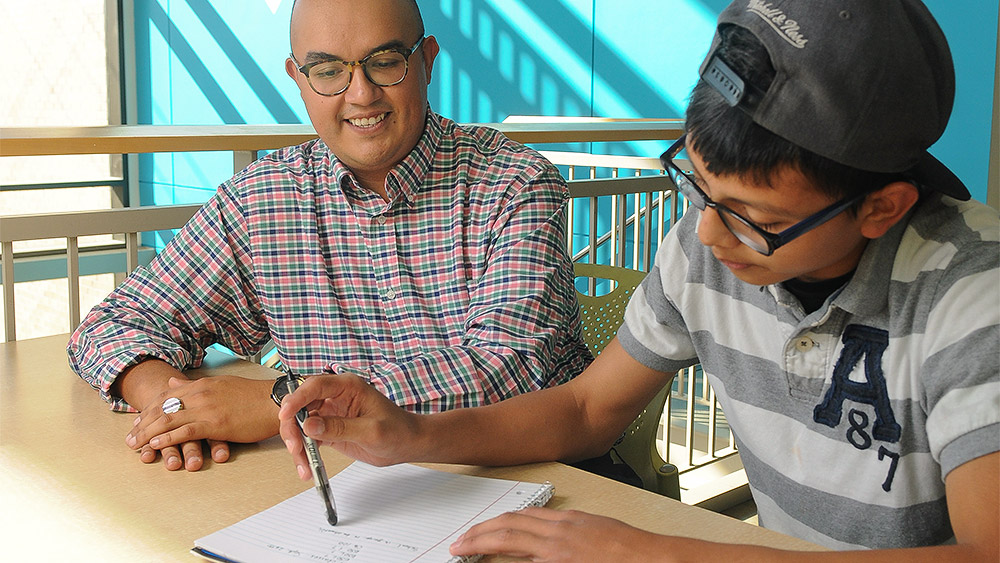 Paraeducator working with a student over a notebook