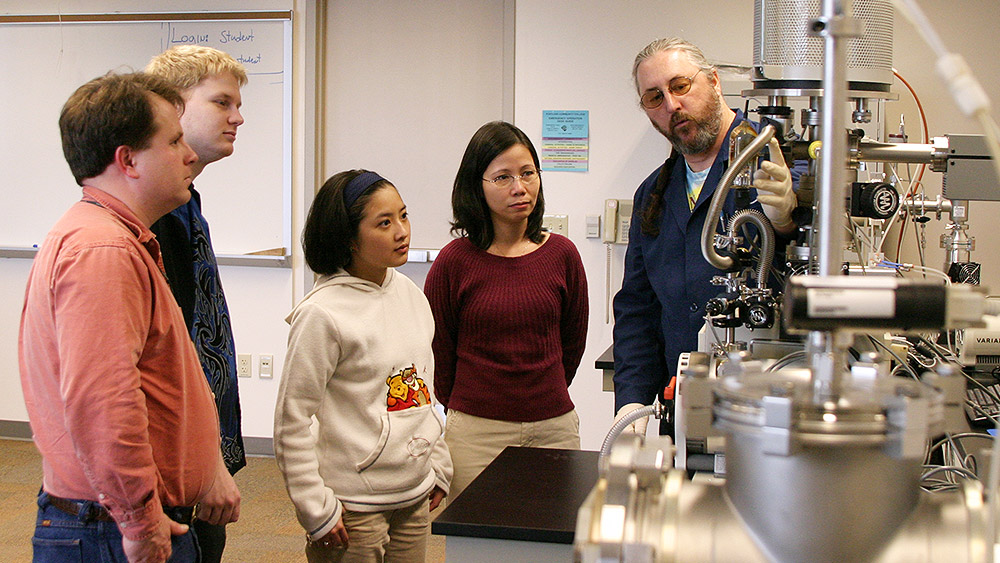 Students watching the instructor go over large electrical equipment in the lab