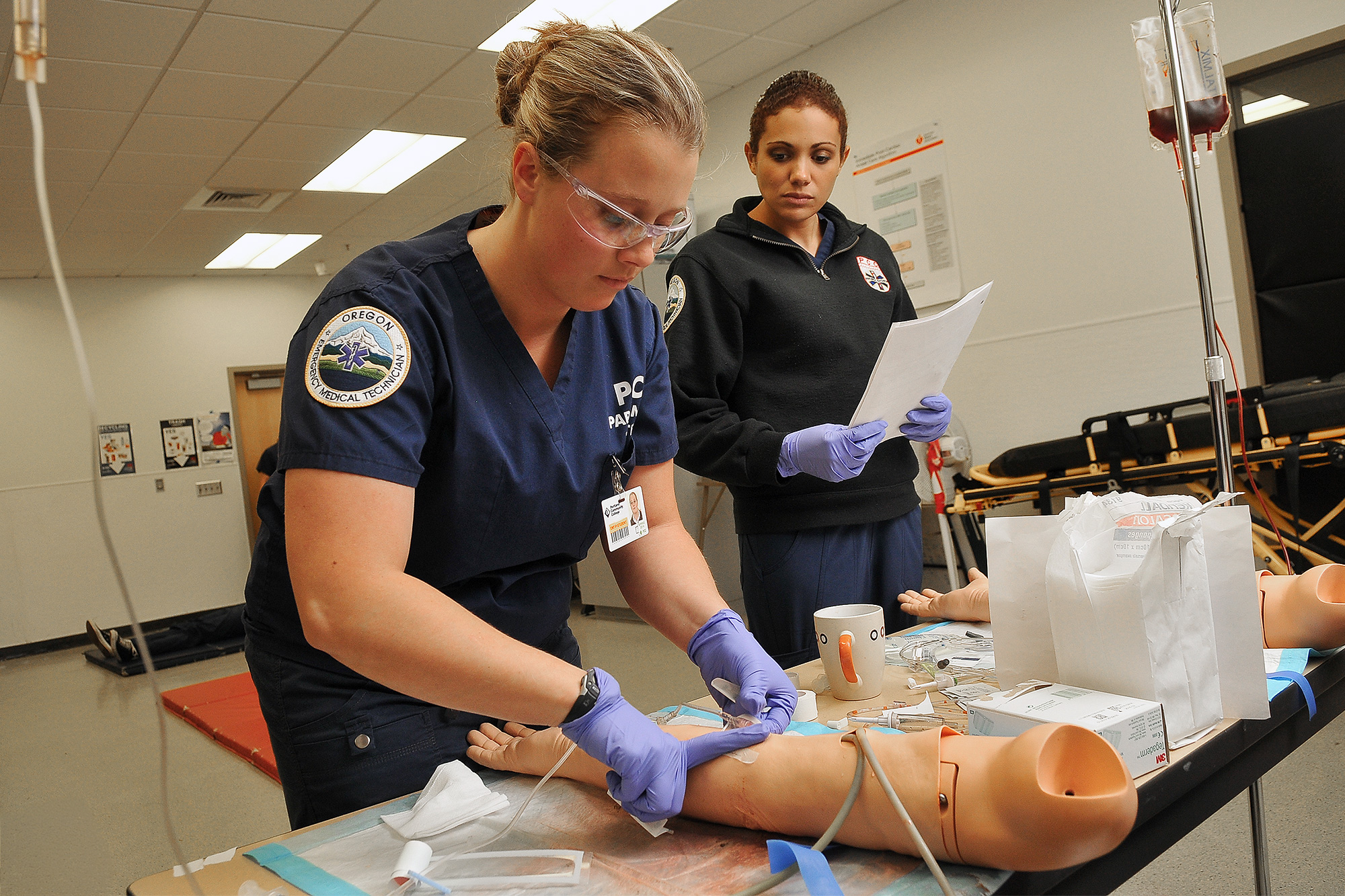 EMS Paramedic student bandaging an injury on a dummy patient's leg