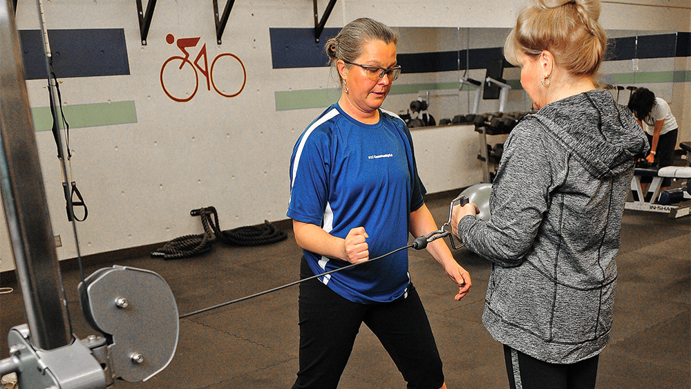 Trainer working with a student on a workout machine