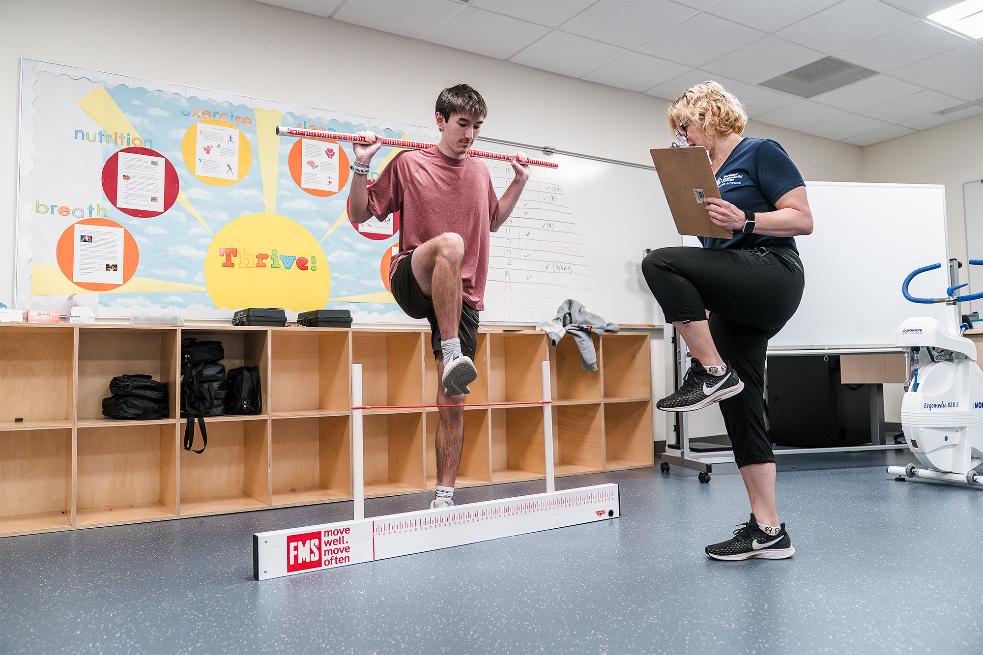 Instructor working with a student individually in class about correct posture during an exercise