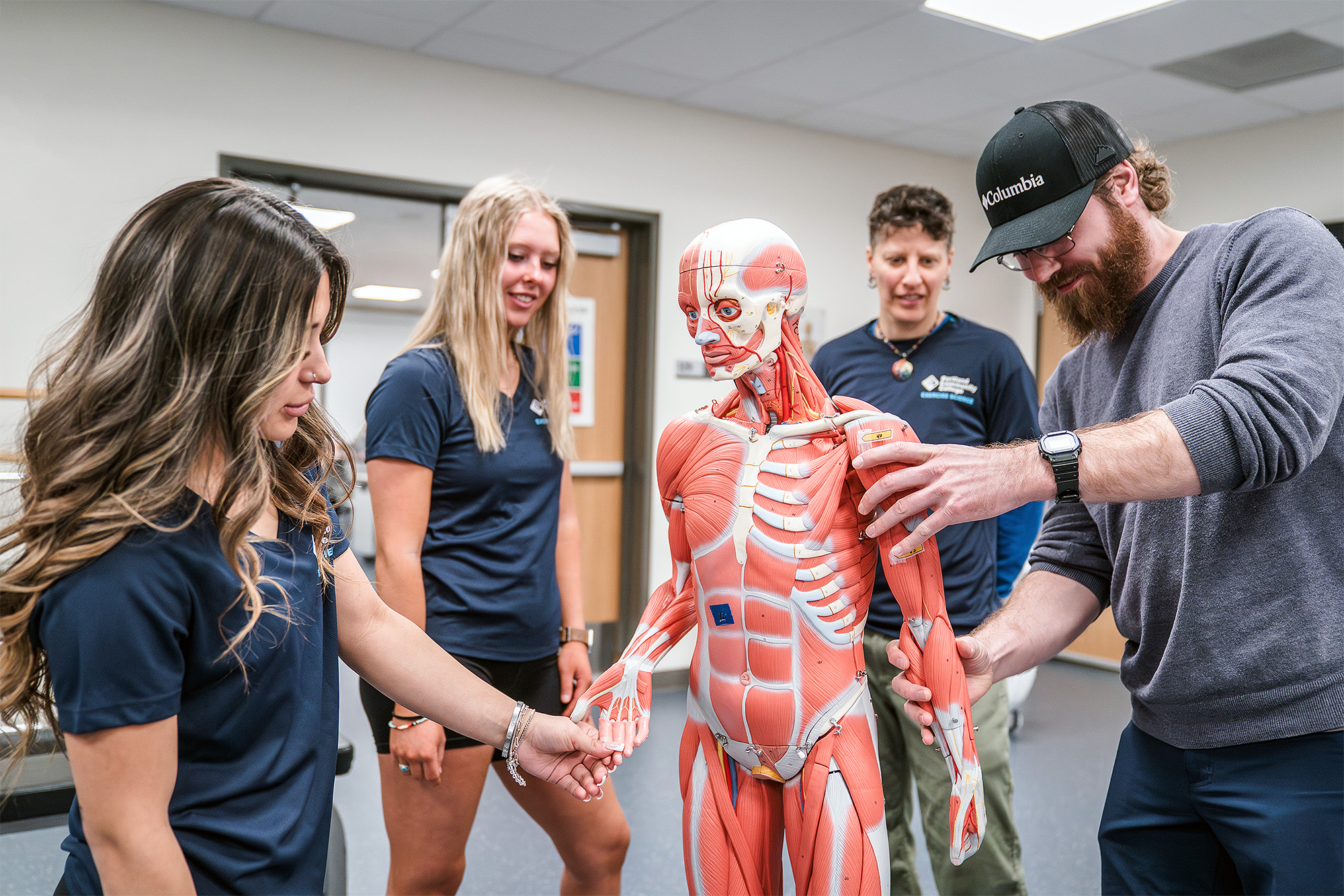 Exercise Science students inspecting a dummy demonstrating human muscles in class