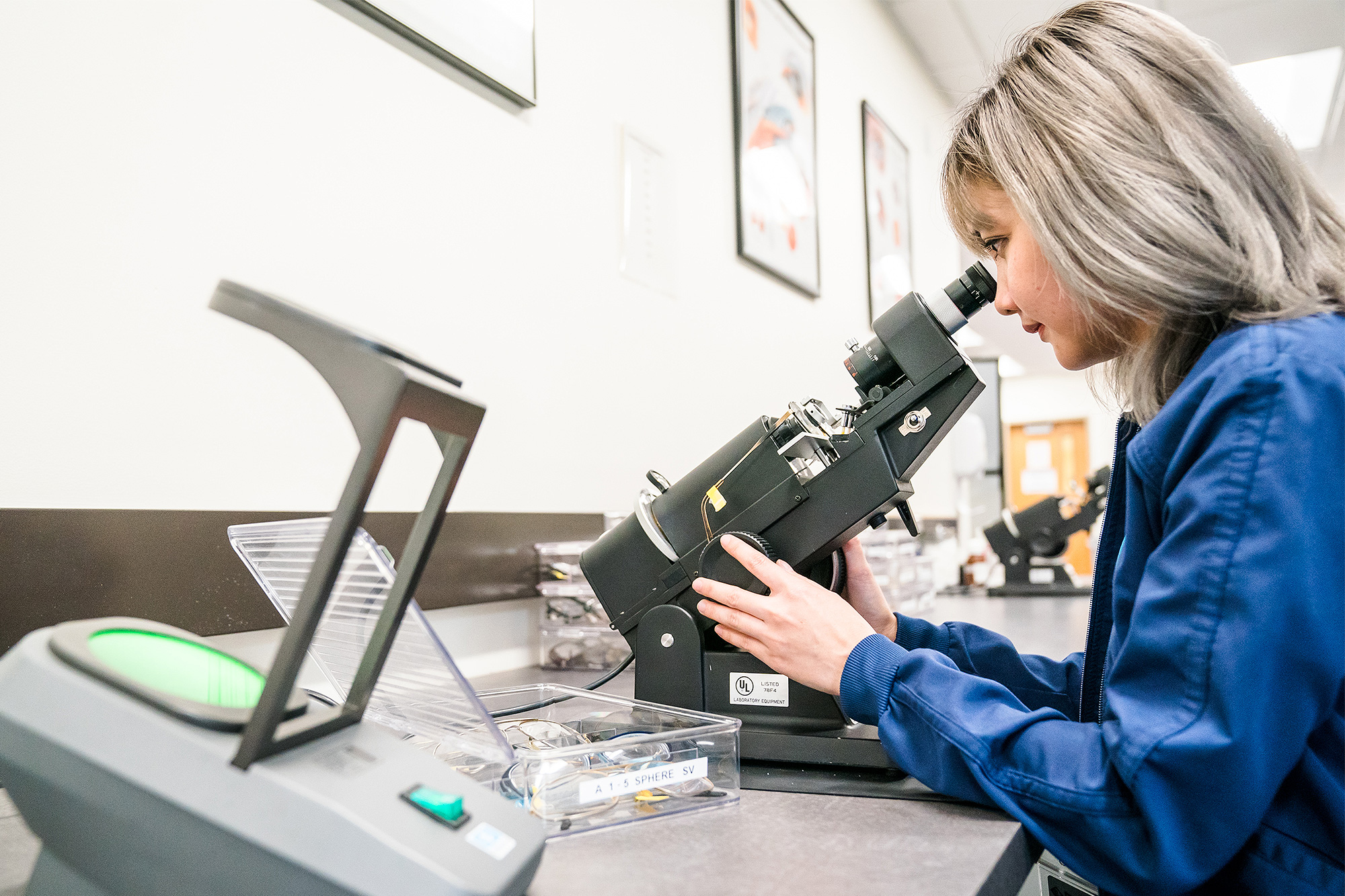 Optician Assistant student looking into a microscope