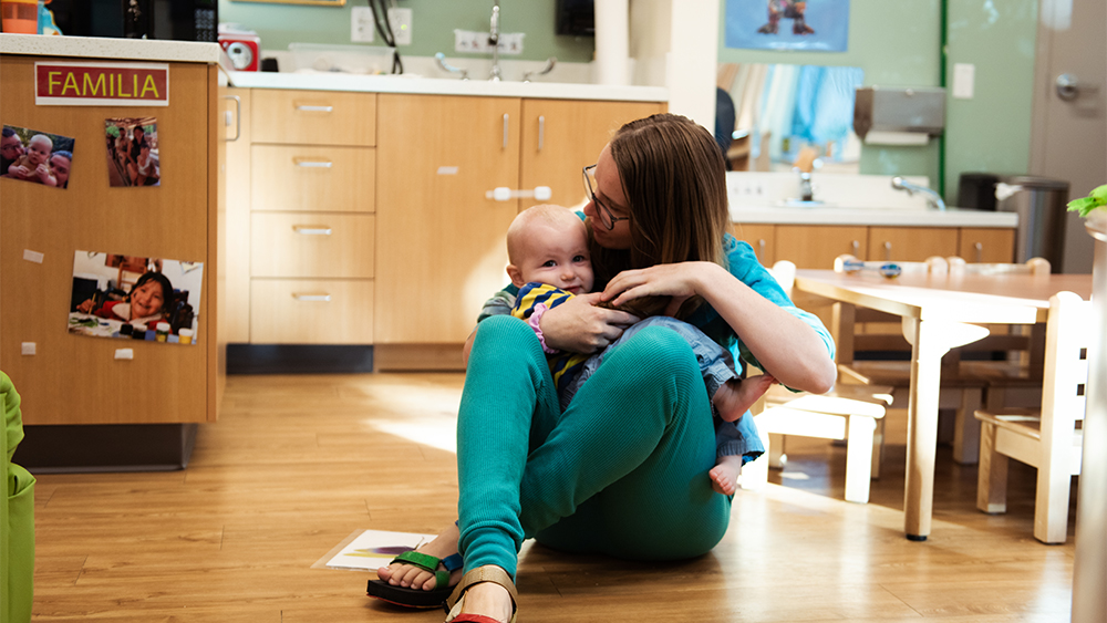 Student holding a young child in a classroom