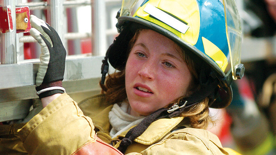 Student in a firefighter uniform working on a fire truck