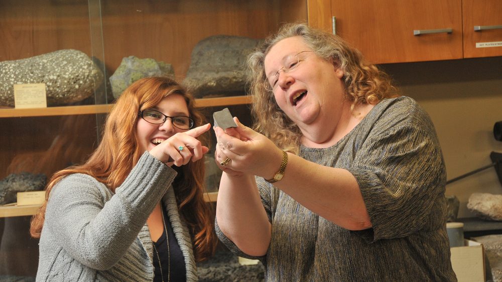 Geology instructor looking at rock with student