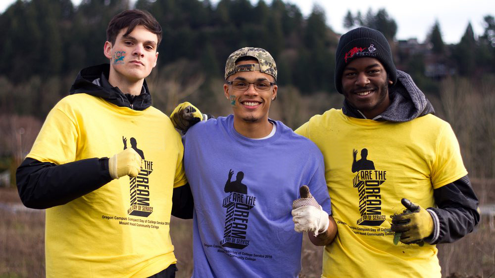 Three students doing work in the community with MLK Day shirts on