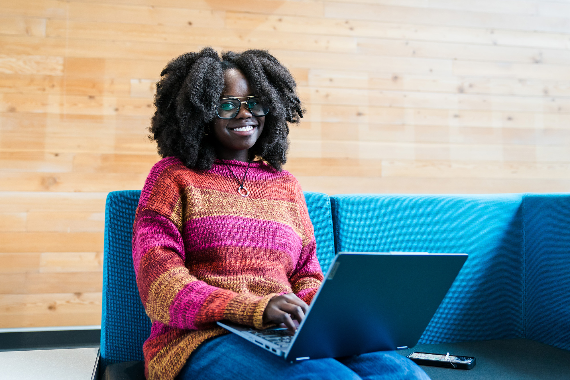Student with a laptop on her lap smiling at the camera