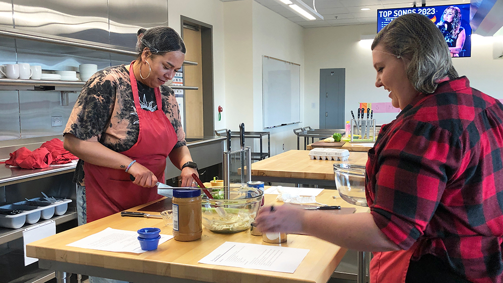 Two students prepping food in a kitchen