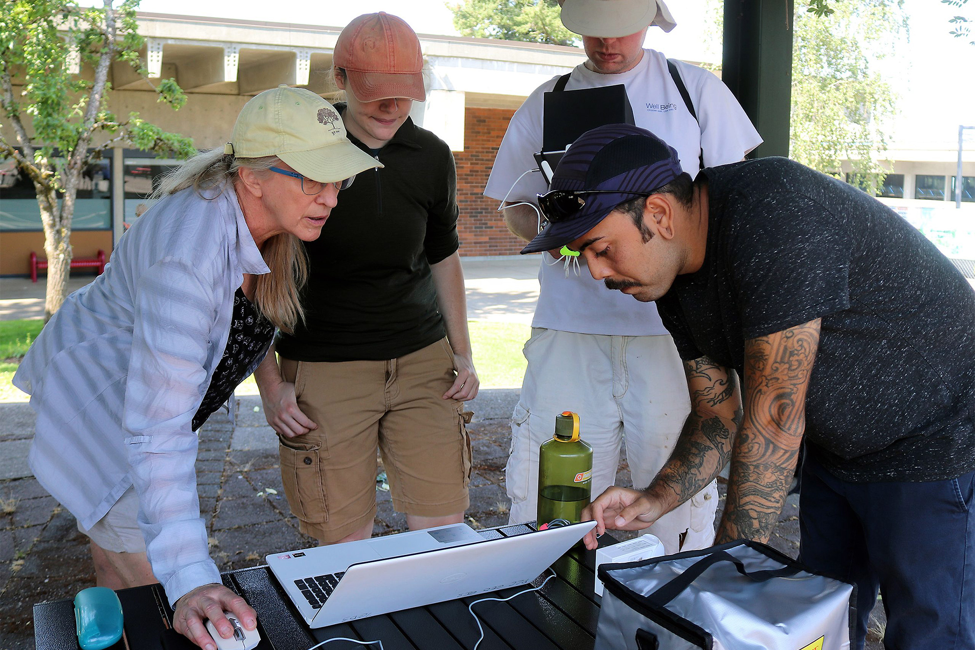 GIS students standing together outside looking at a computer