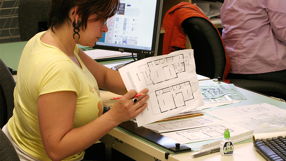 Student at a computer looking through blueprints on the table