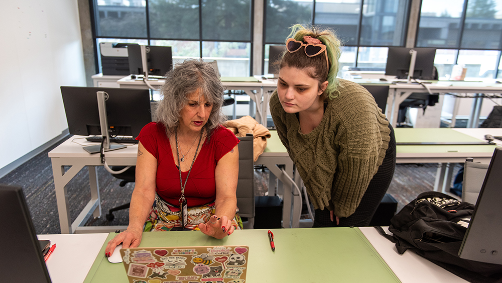 Student looking at a teacher's laptop in a classroom