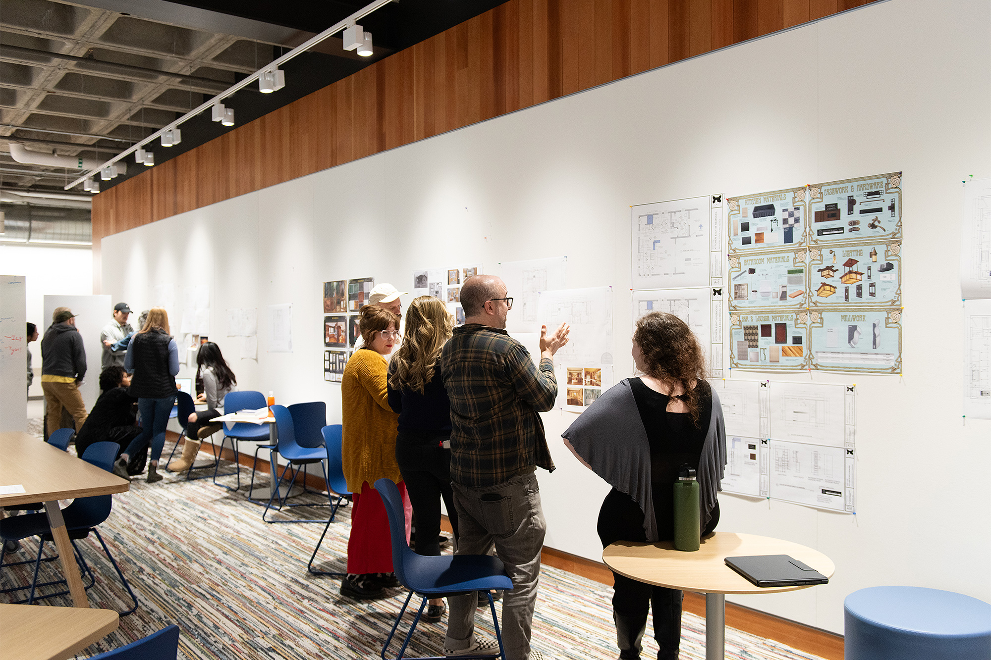 Interior Design students standing and discussing plans during a project presentation