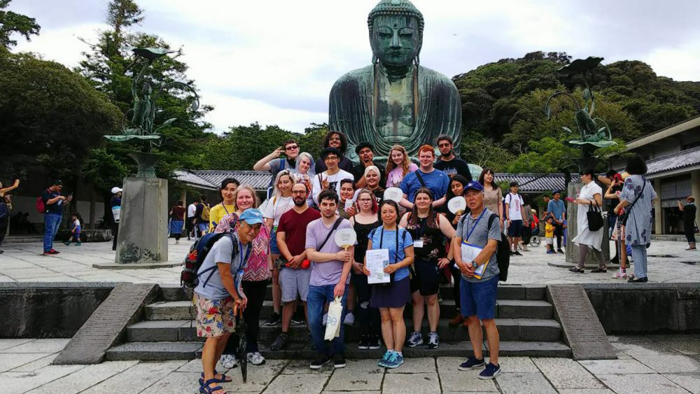 PCC students standing in front of a Buddha statue on a trip to Japan