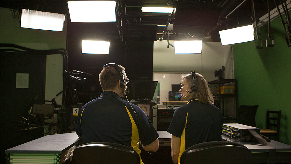 Two journalists in front of studio lights