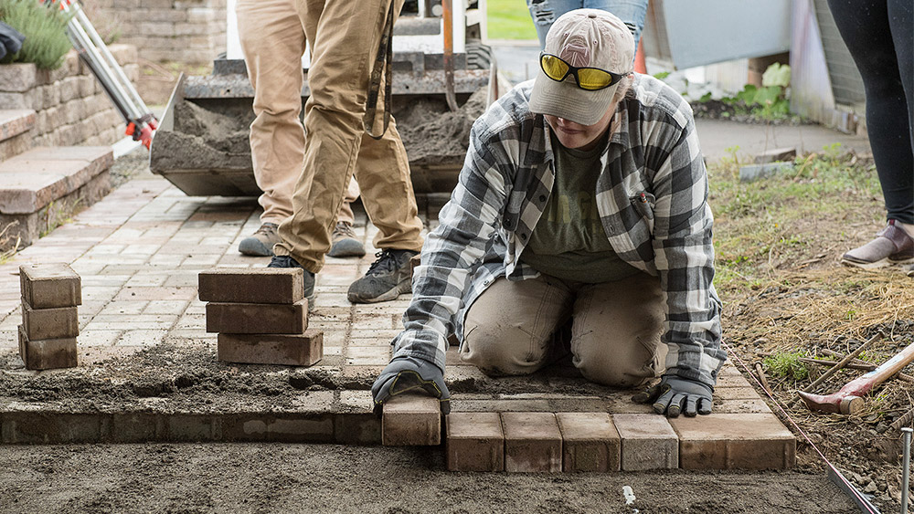 Student laying pavers at a job site for a path